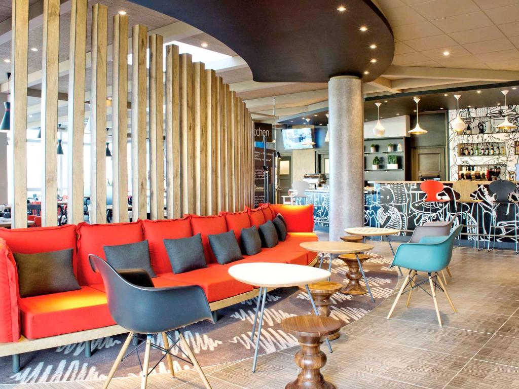 华沙宜必思华沙奥斯托布朗斯卡酒店的大堂设有红色的沙发和桌椅
