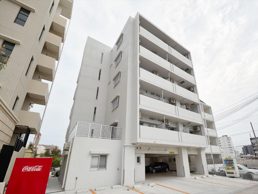 北谷町M´s Stay Okinawa的一座大型白色公寓大楼,设有停车场