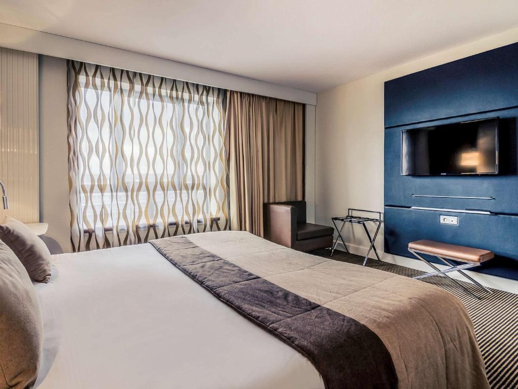 塞尔吉塞尔吉蓬图瓦兹中心美居酒店的酒店客房设有一张大床和一台电视机。