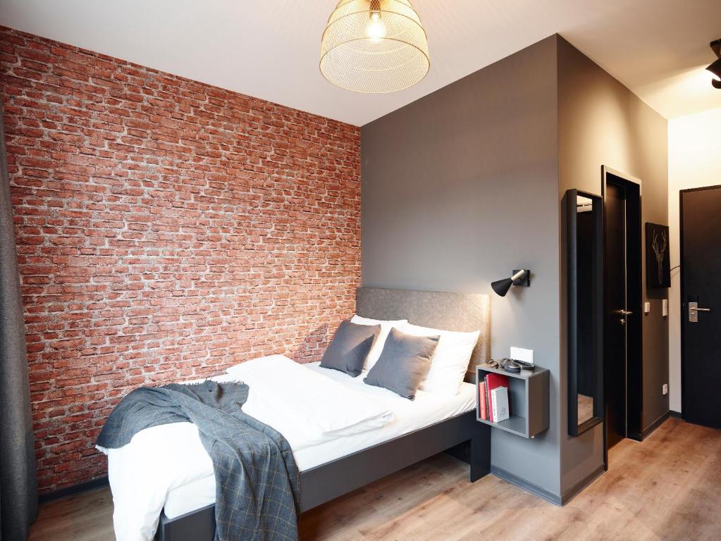 汉堡PHNX Aparthotel Hamburg的一间卧室设有砖墙和一张床