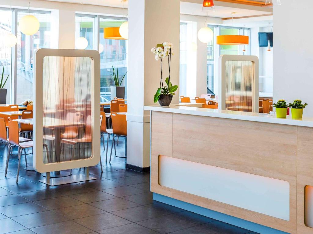 鲁汶埃塔鲁汶中心酒店的餐厅设有两面镜子和一张桌子及椅子