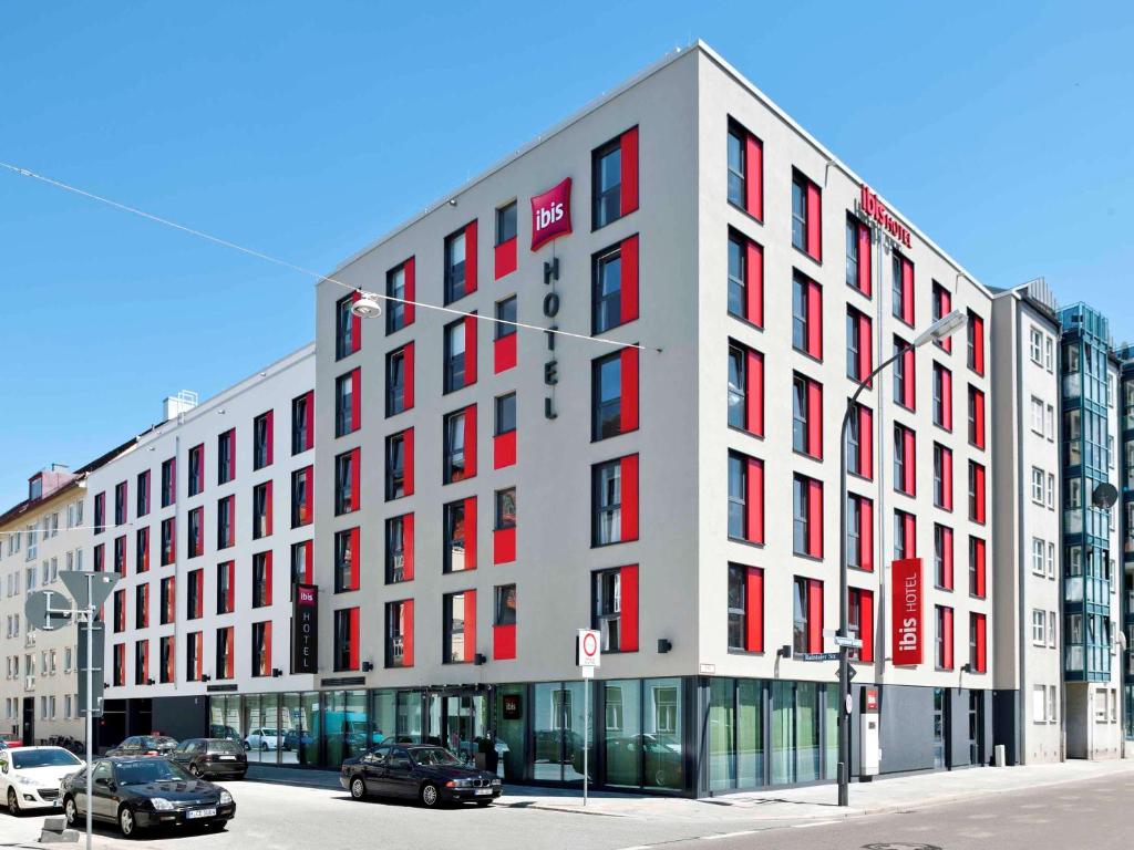 慕尼黑宜必思慕尼黑市苏德酒店的街道上一座白色的大建筑,设有红色窗户