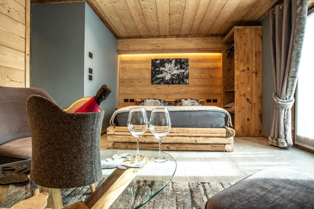 布勒伊-切尔维尼亚Alpine Rooms Guesthouse的一间房间,配有床和桌子上的两杯酒杯