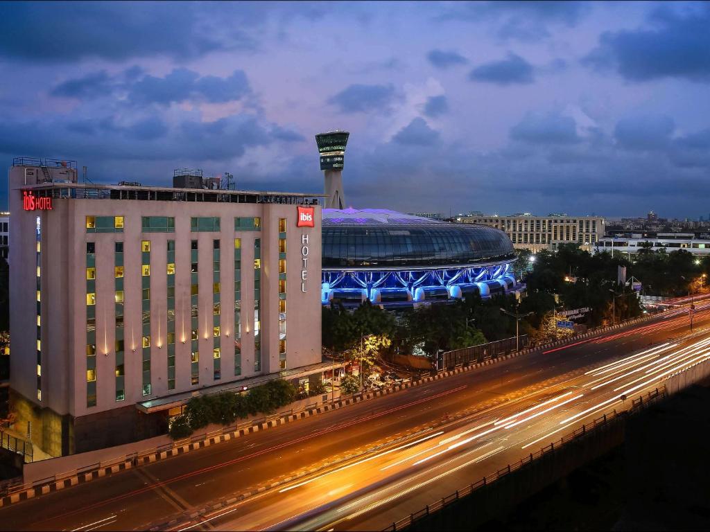 孟买ibis Mumbai Airport - An Accor Brand的一座大型建筑,在晚上有一个体育场