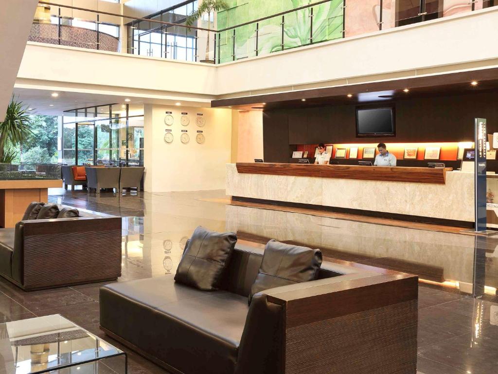 美娜多诺富特曼纳多高尔夫会议度假酒店的大楼内一个带沙发和电视的大堂