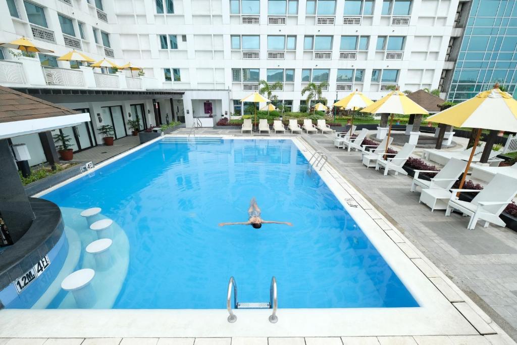 宿务Quest Hotel & Conference Center Cebu的游泳池,带椅子,有人游泳