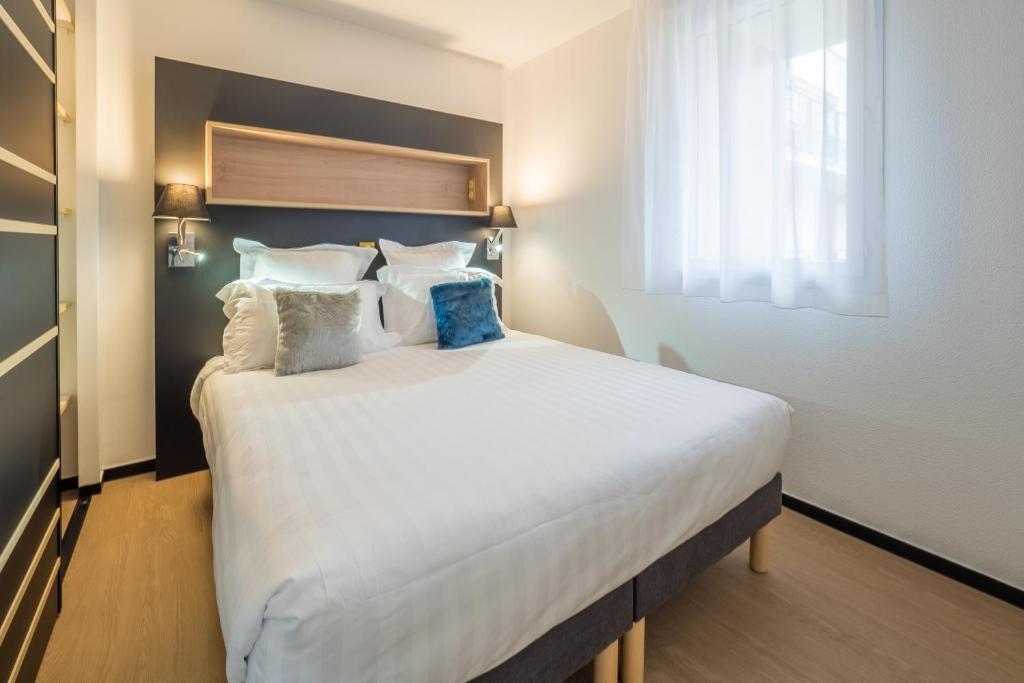 格勒诺布尔Apparthotel Le Hüb Grenoble的卧室里有一张大床，床单和枕头都是白色的