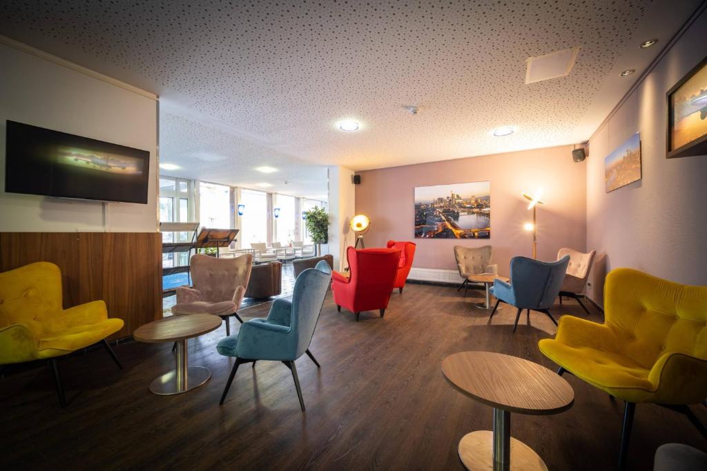 默费尔登-瓦尔多夫Anor Hotel & Conference Center Frankfurt Airport的一间设有五颜六色的椅子和桌子的等候室