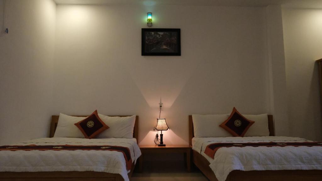 邦美蜀Khách sạn Hiệp Thạnh的一间设有两张床和一盏墙上灯的房间