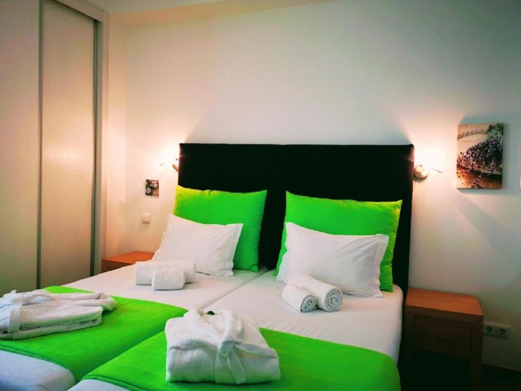 丰沙尔Casa dos Avós Apartments的一张带绿色和白色床单及枕头的床