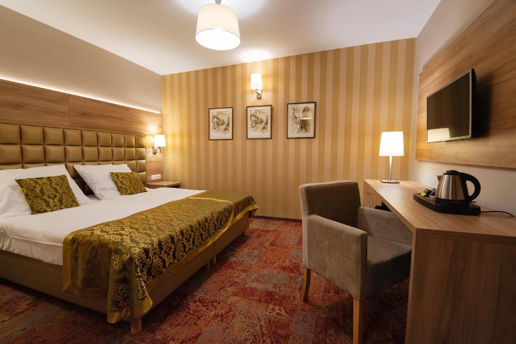 OlesnoHotel Olesno的酒店客房配有一张床、一张书桌和一台电视。