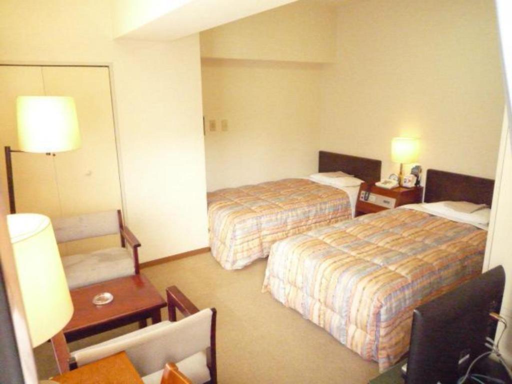 川崎Sky Heart Hotel Kawasaki / Vacation STAY 80807的酒店客房设有两张床和一张桌子。