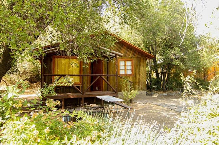圣何塞德迈波Cabañas Parque Almendro的小屋前方设有长凳的小木屋
