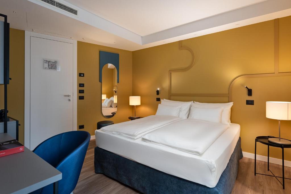 格拉迪斯卡迪松佐HT Hotel Trieste的卧室配有一张白色大床和一张书桌