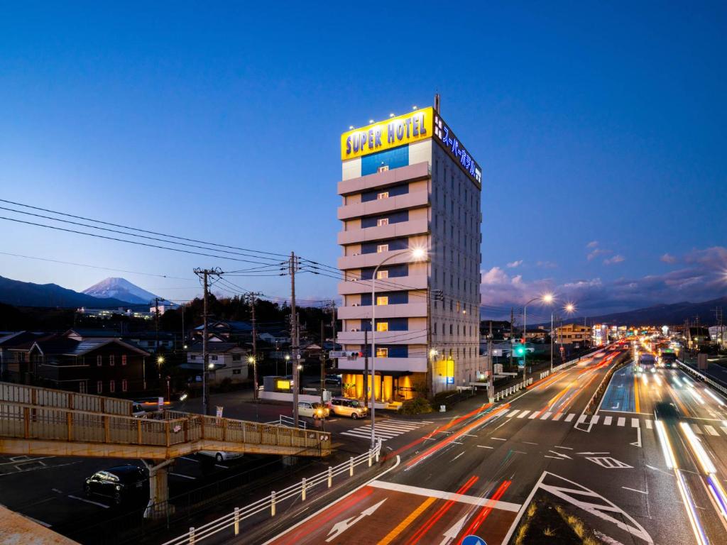 长泉Super Hotel Nagaizumi Numazu Inter的城市街道上一座高大的建筑,上面有标志
