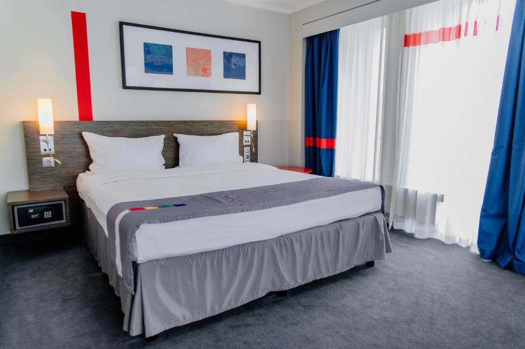 彼得罗扎沃茨克皮特尔酒店的一间卧室配有一张带蓝色窗帘的大床