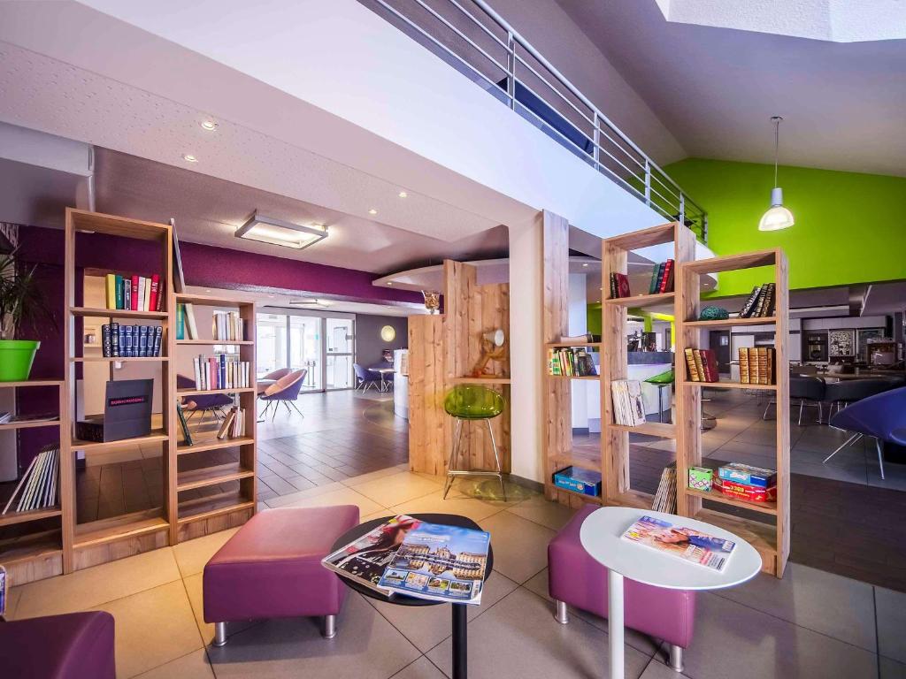 布里夫拉盖亚尔德布利维西部宜必思尚品酒店的一间设有书架、桌子和紫色椅子的房间
