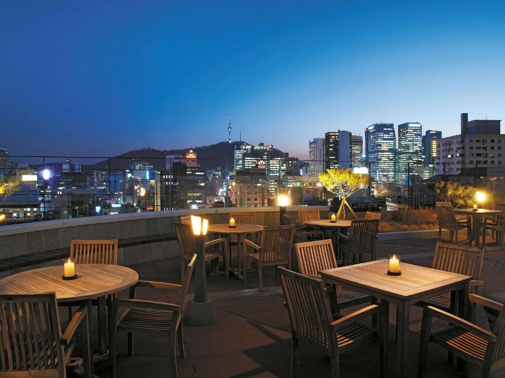 首尔ibis Ambassador Seoul Insadong的一个带桌椅的屋顶露台,享有城市天际线