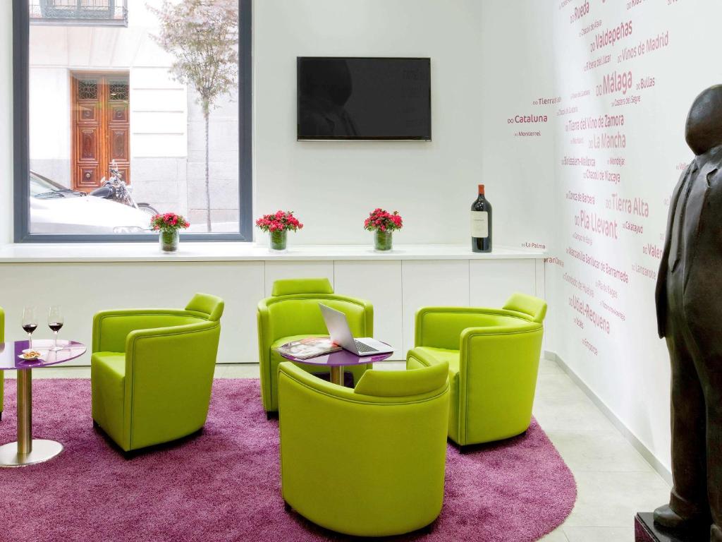 马德里马德里普拉多宜必思尚品酒店的一间设有绿色椅子、桌子和电视的等候室