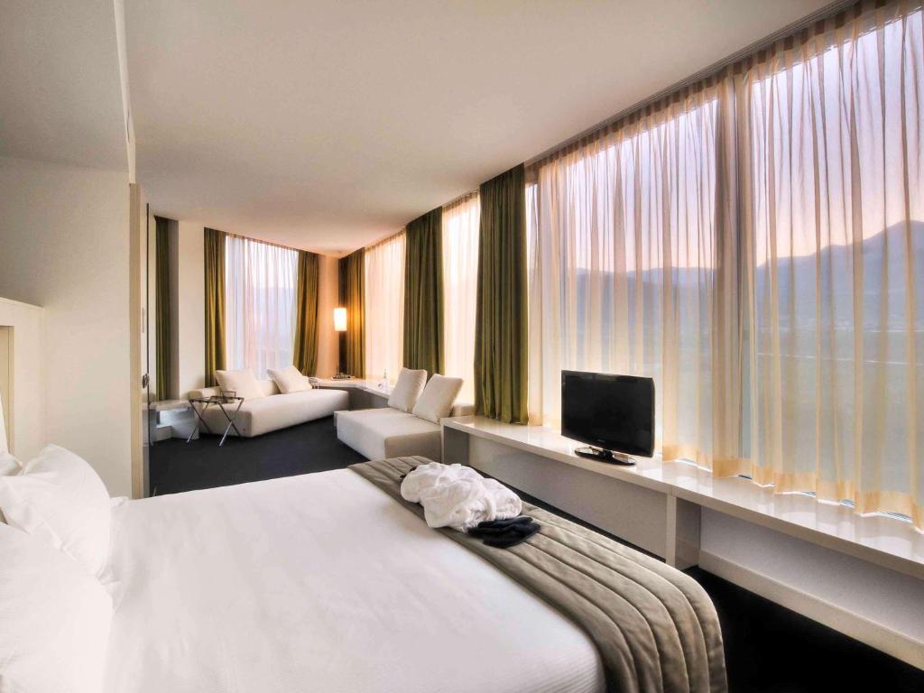 罗韦雷托罗韦雷托纳雷克伯美居酒店的酒店客房设有一张床和一个大窗户