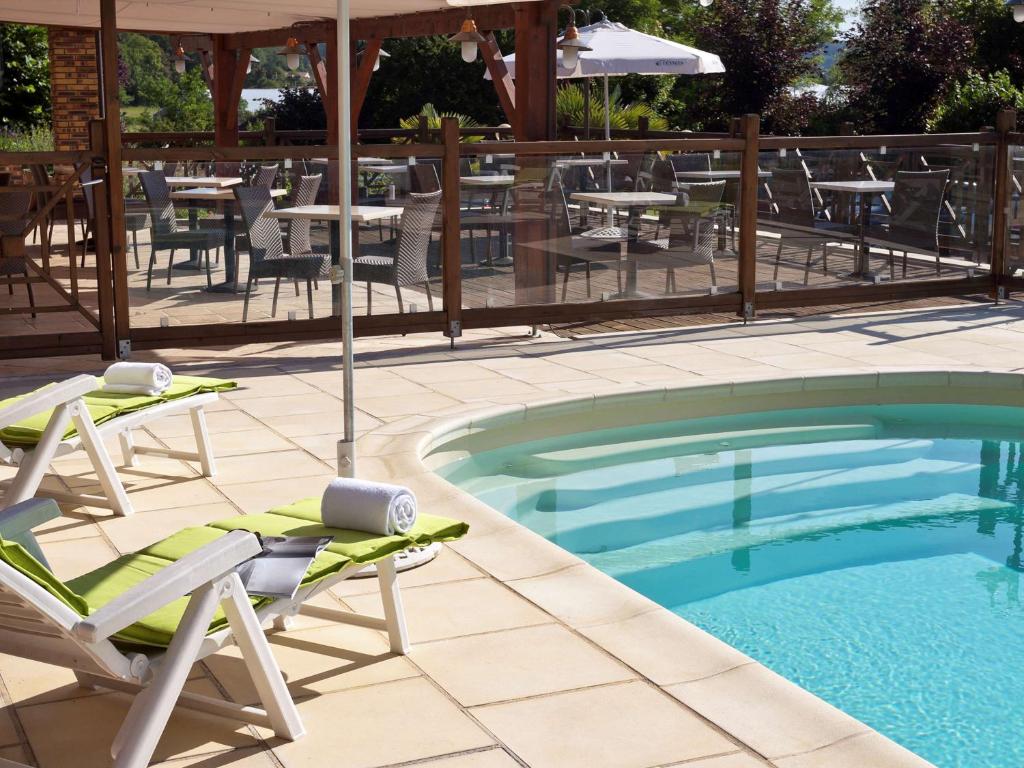 特雷利萨克四季佩里杰特雷利萨克酒店的游泳池配有椅子、遮阳伞和桌子