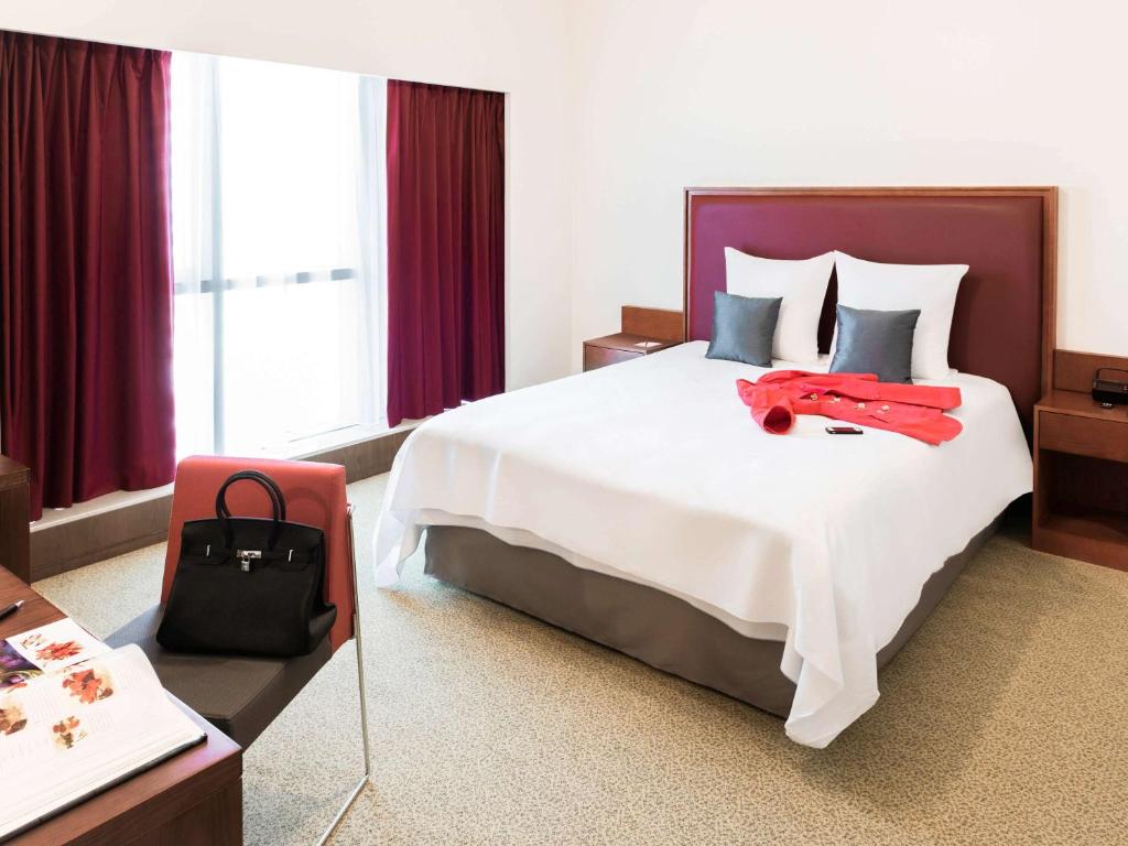 富查伊拉Aparthotel Adagio Fujairah的酒店客房设有一张大床,上面装有红色钱包