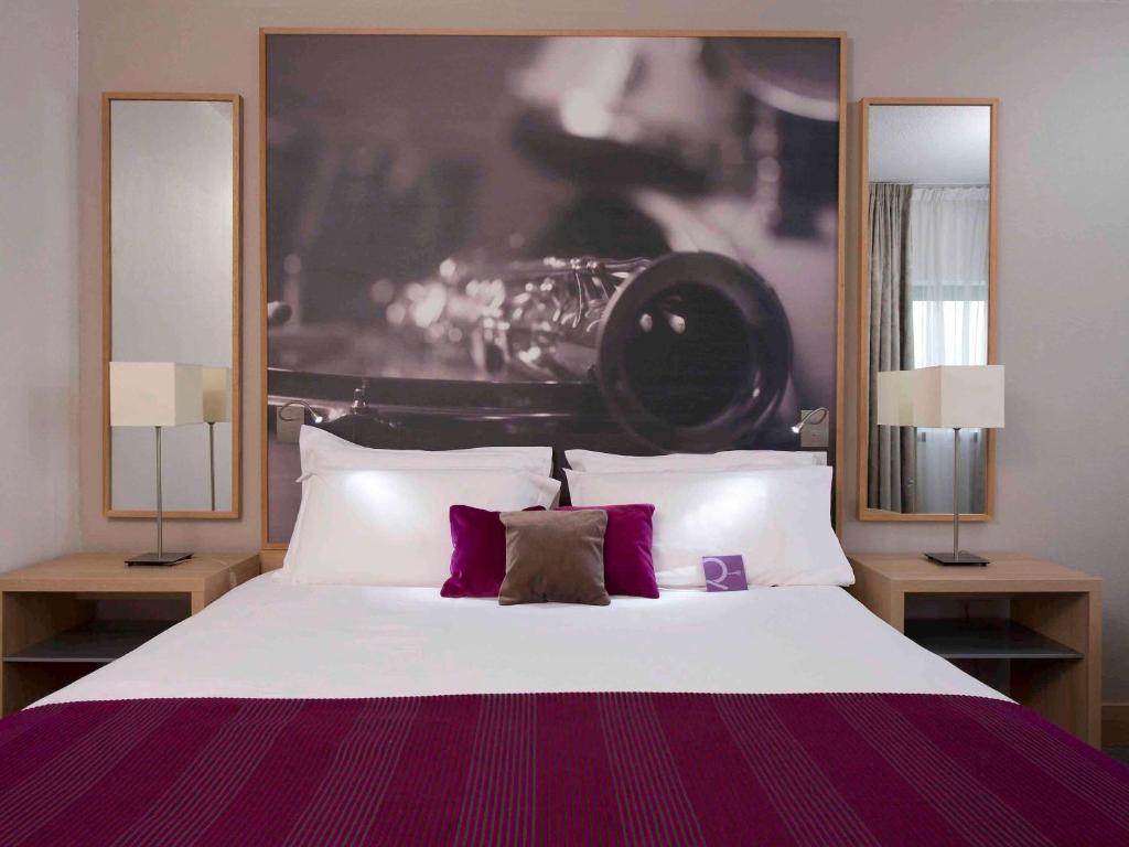 巴黎巴黎爱乐厅拉维莱特19号美居酒店的一间卧室配有一张大床和两盏灯