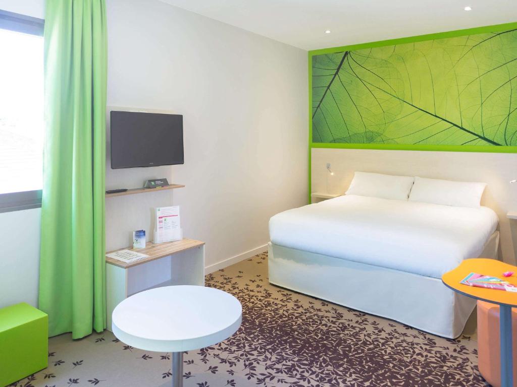 洛特河畔的维伦纽夫维伦纽夫宜必思尚品酒店的卧室配有白色的床和绿色的墙壁