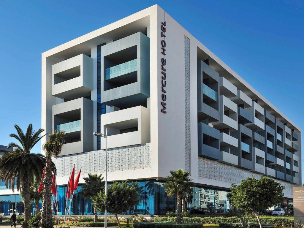 纳祖尔Mercure Nador Rif的一座白色的大建筑,前面有棕榈树