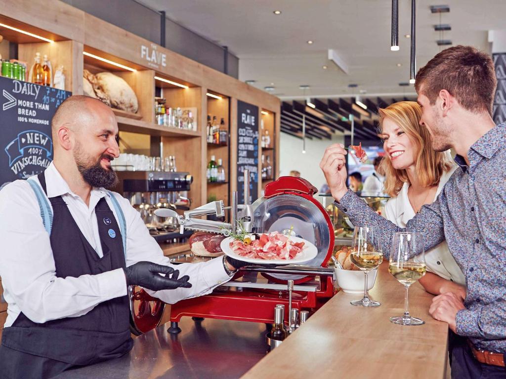 慕尼黑诺富特慕尼黑市阿努尔福帕克酒店的女人在酒吧给男人一盘食物