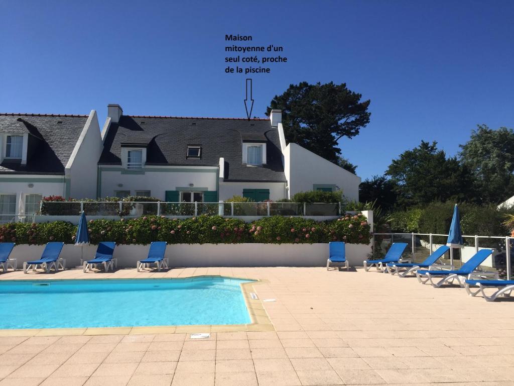 洛克马里亚Maison de vacances de 56 m2 dans résidence avec piscine chauffée proche plages的一个带椅子的游泳池和一个背景建筑