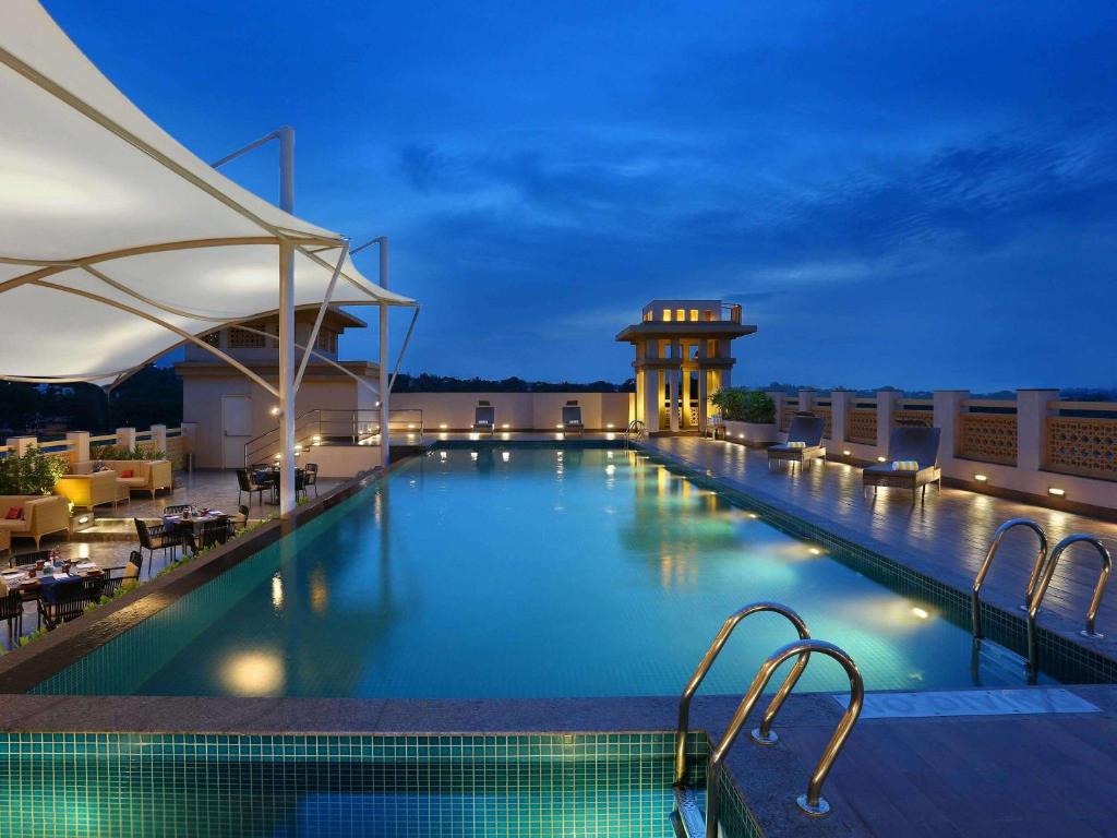 迈索尔Grand Mercure Mysore - An Accor Brand的夜间酒店屋顶的游泳池