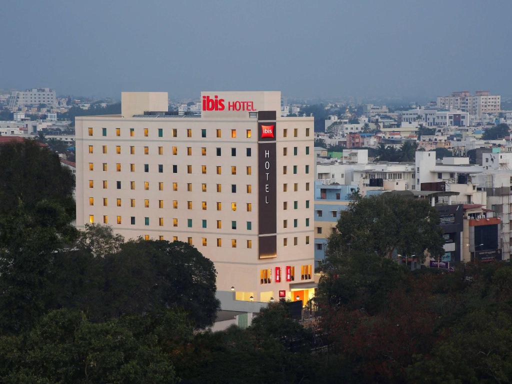 哥印拜陀ibis Coimbatore City Centre - An Accor Brand的一座白色的大建筑,上面有公共汽车的货柜标志