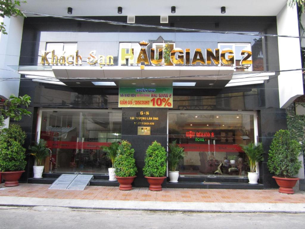 芹苴Hau Giang 2 Hotel Cần Thơ的前方有盆栽植物的餐厅前方的商店