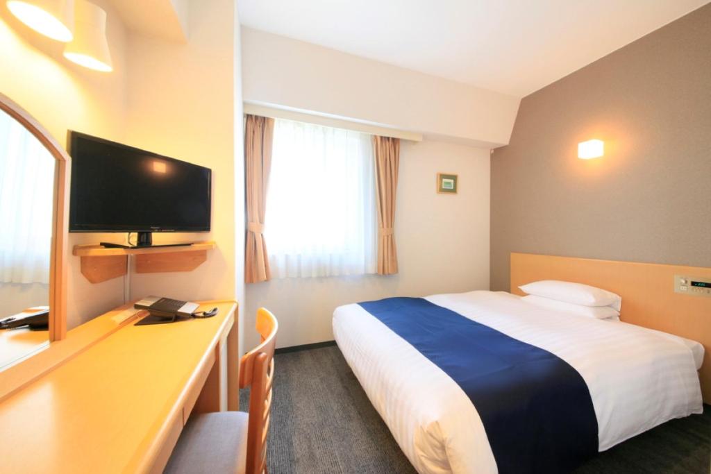 东京大城市酒店的酒店客房配有一张床和一张书桌及一台电视