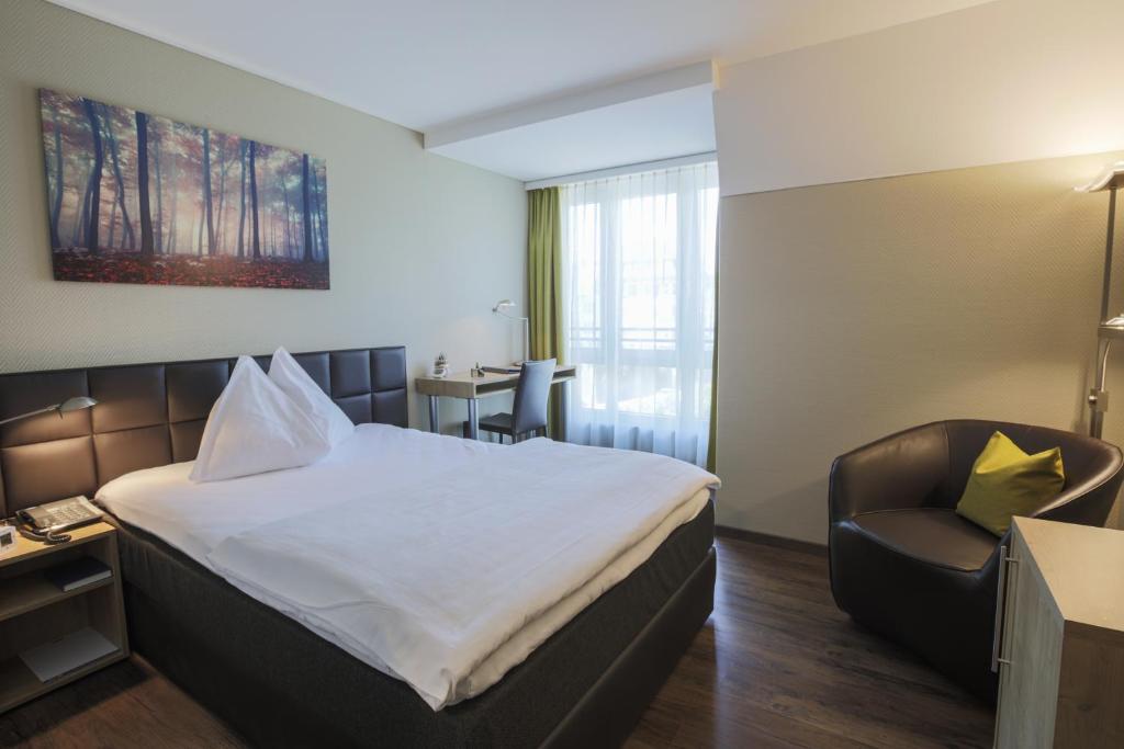 黑里绍Herisau Swiss Quality Hotel的配有一张床和一把椅子的酒店客房
