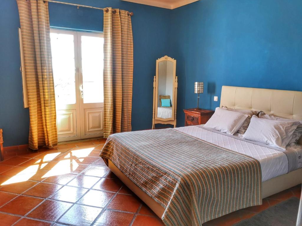 蒙萨拉什圣卡塔里娜山旅馆的一间卧室配有一张蓝色墙壁的床和一扇窗户
