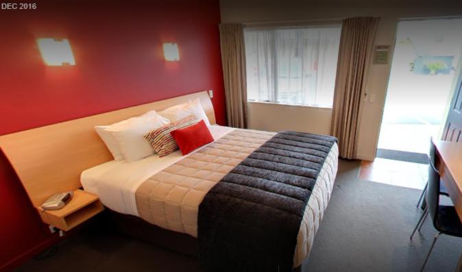 汉密尔顿公园景汽车旅舍的一间卧室设有一张带红色墙壁的大床