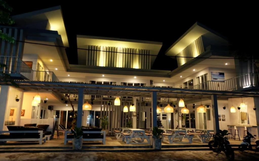 克罗柏坎Pom Pom's Bali Apartments的一座带桌椅的大型建筑,晚上