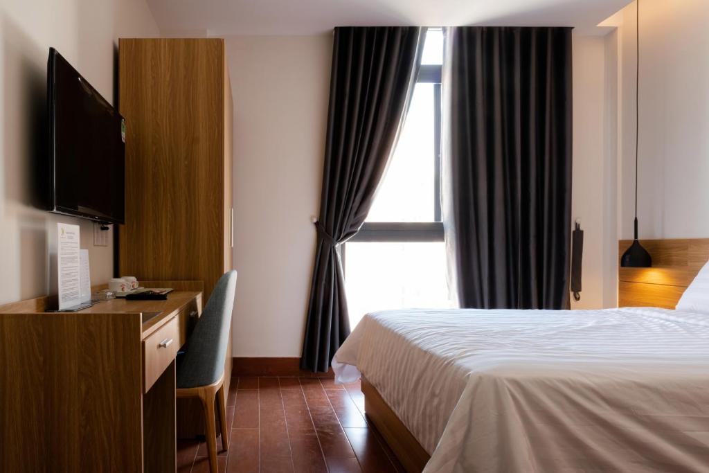 土龙木市Khang Điền Hotel的配有一张床、一张书桌和一扇窗户的酒店客房