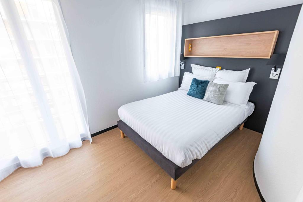 格勒诺布尔Apparthotel Le Hüb Grenoble的一间卧室配有带白色床单和蓝色枕头的床。