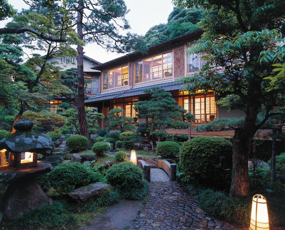 丰冈市西村屋 本馆的一座花园,位于一座树木和灯光的建筑前