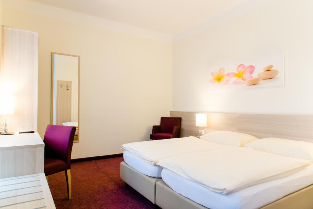 格拉茨附近卡尔斯多夫彭德尔酒店的一间卧室配有一张床、两把椅子和镜子