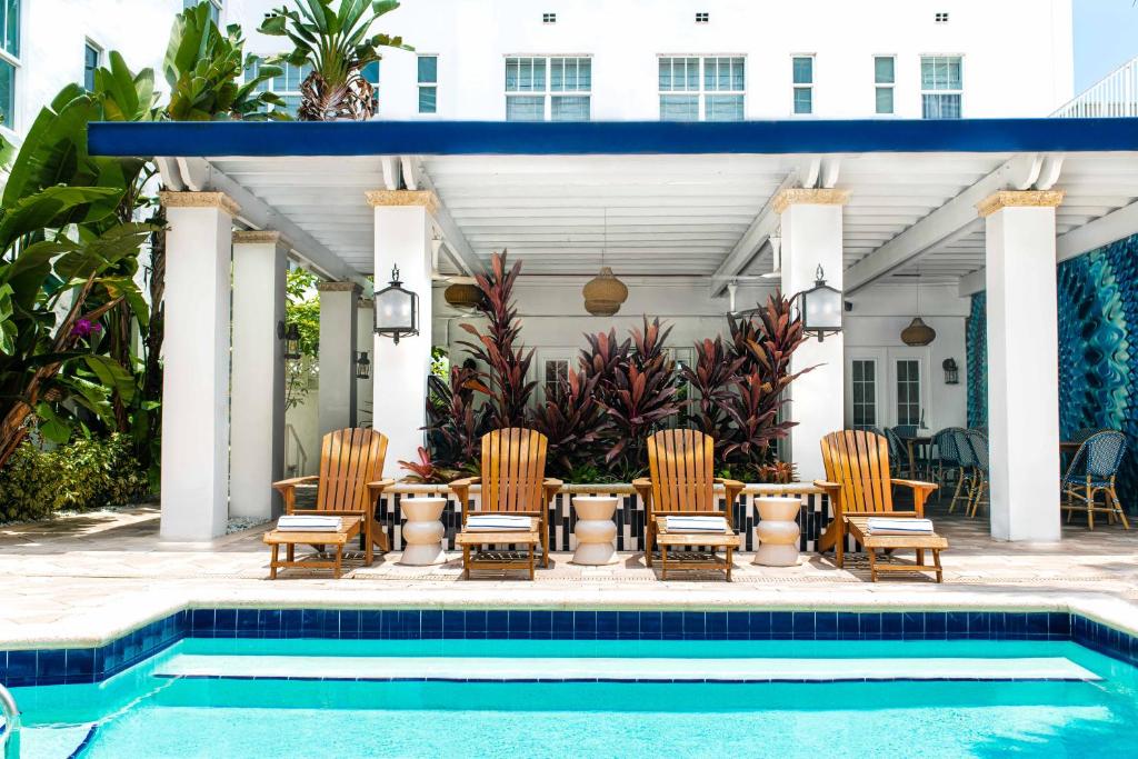 迈阿密海滩Blue Moon Hotel的一个带椅子和桌子的庭院,毗邻一个游泳池