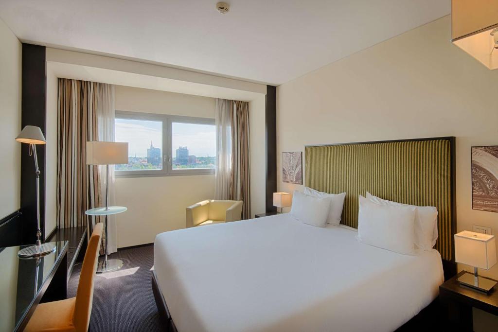 帕多瓦NH帕多瓦酒店的酒店客房设有一张白色大床和一个窗户。