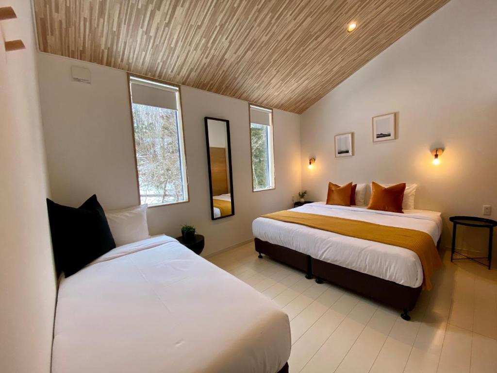 白马村ZEN CHALETS Hakuba的一间卧室设有两张床和两个窗户。