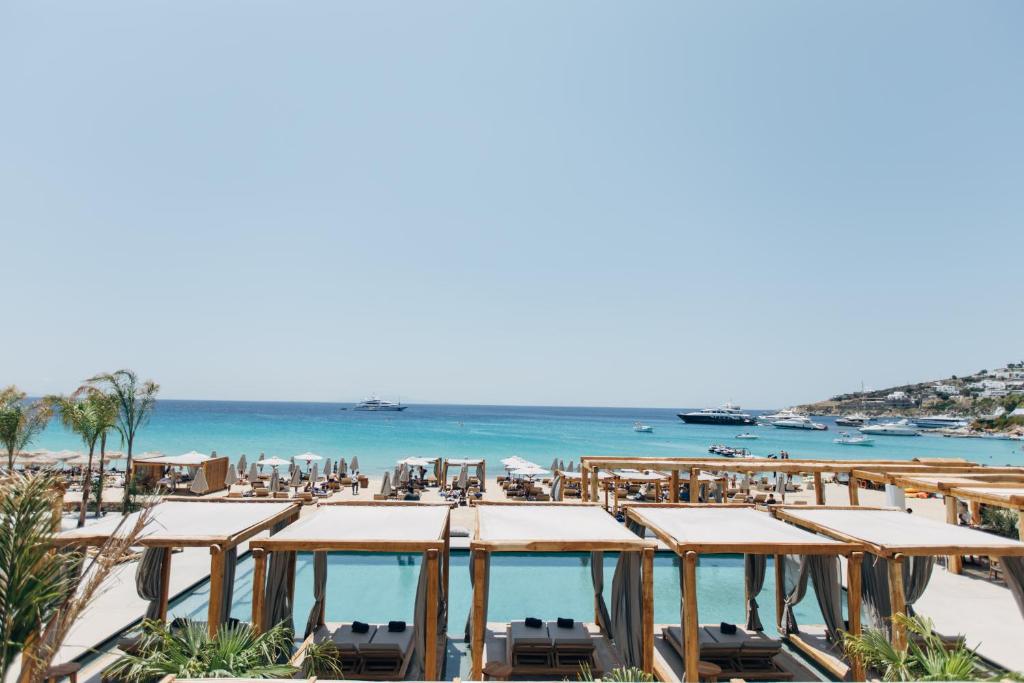 普拉迪斯亚罗斯米科诺斯布兰科酒店的享有海滩美景,配有椅子和遮阳伞