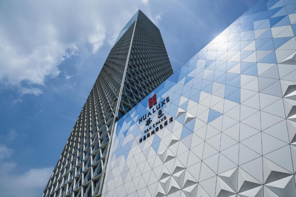 南昌南昌绿地华邑酒店的一座高大的玻璃建筑,上面有标志