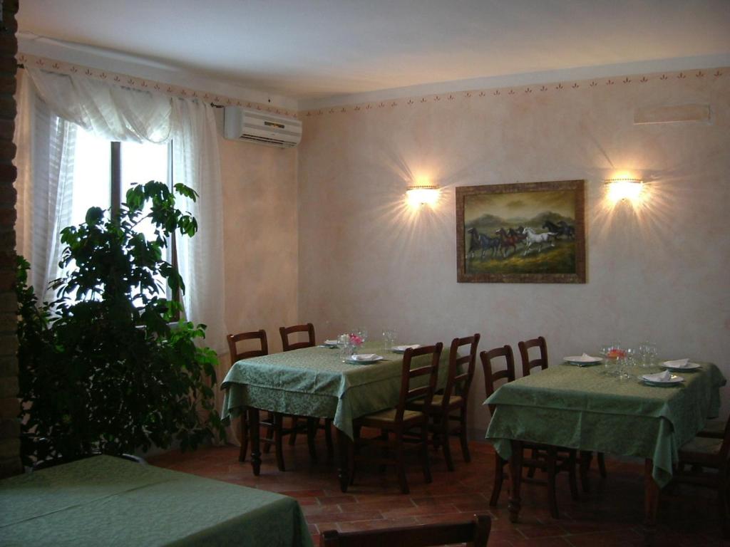 Spino dʼAddaAgriturismo Cascina Gilli的用餐室配有桌椅,墙上挂有绘画作品