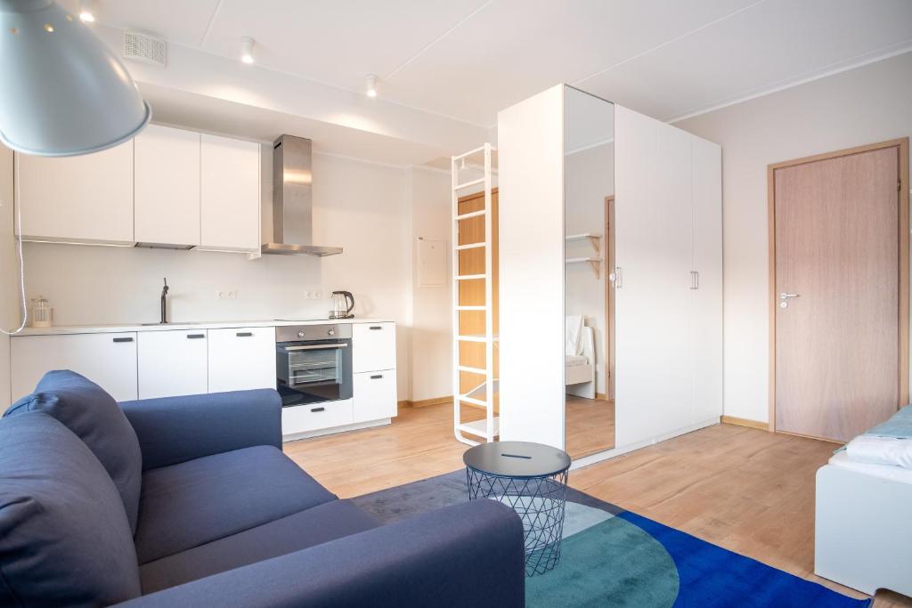 塔林Modern Mustamäe Apartments - Free parking的一间带蓝色沙发的客厅和一间厨房